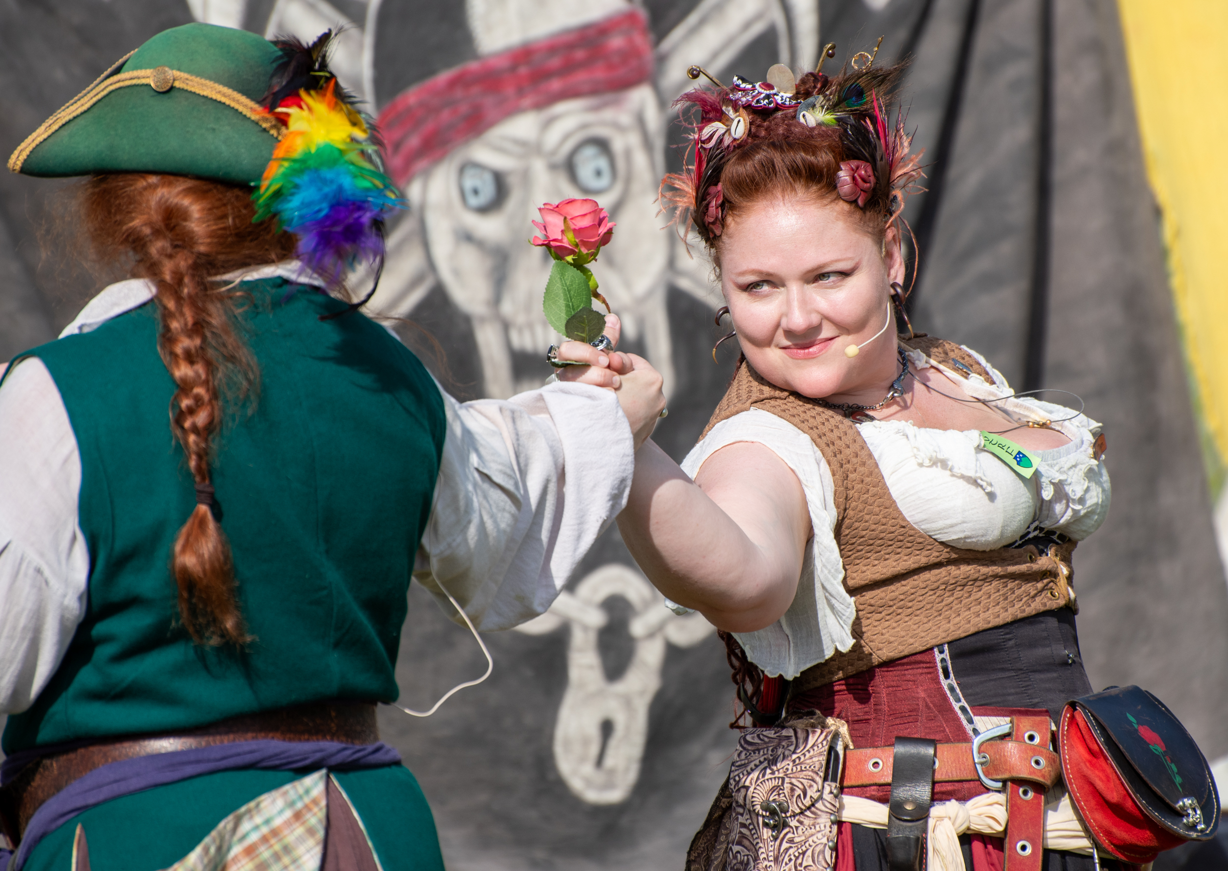 A photograph of two female pirates beginning to tango while they both hold the same rose. One pirate has her back to the camera, the other's face is visible, and she can be seen smirking at her dance partner
